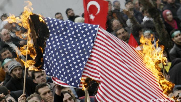 Demonstrators burn a U.S. flag