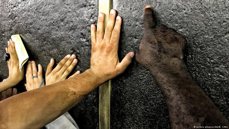 Muslim Hajj pilgrims touch the Kaaba stone as they circumambulate around the Kaaba, Islam's holiest site, located in the centre of the Masjid al-Haram or Grand Mosque in the holy city of Mecca, Saudi Arabia on 19 August 2018 (photo: picture alliance/AA/M. Ciftci)
