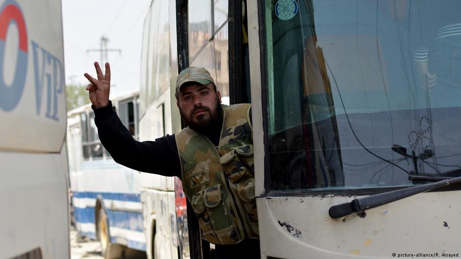 A man gestures from a bus of the first convoy carrying members of the Free Syrian Army (FSA) and civilians as the convoy departs from the FSA-controlled area of Yarmouk Camp in southern Damascus under the Yarmouk camp evacuation agreement, as part of the compulsory evacuation, on 3 May 2018 (photo: picture-alliance/R. Alsayed)