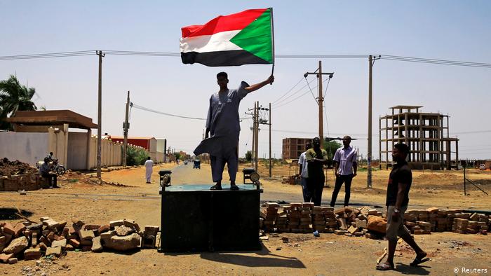 A protester stands on a block holding up the national flag (photo: Reuters)