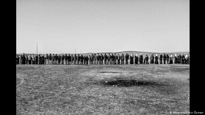 A chain of Kurds stands in a barren landscape (photo: Magnum/Emin Ozmen)