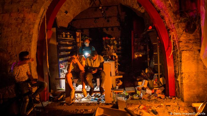 A group of men sit near the entrance of a shop damaged during the explosion in Beirut (photo: Getty Images/D. Carde)