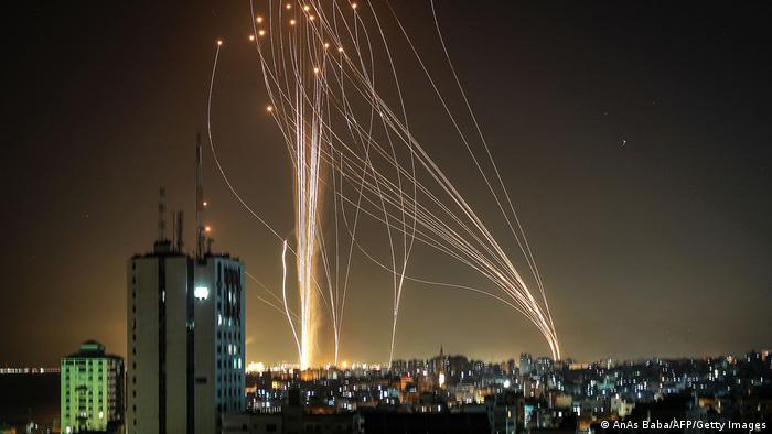 Dozens of rockets rise into the air in a long exposure that lets them be seen over Tel Aviv