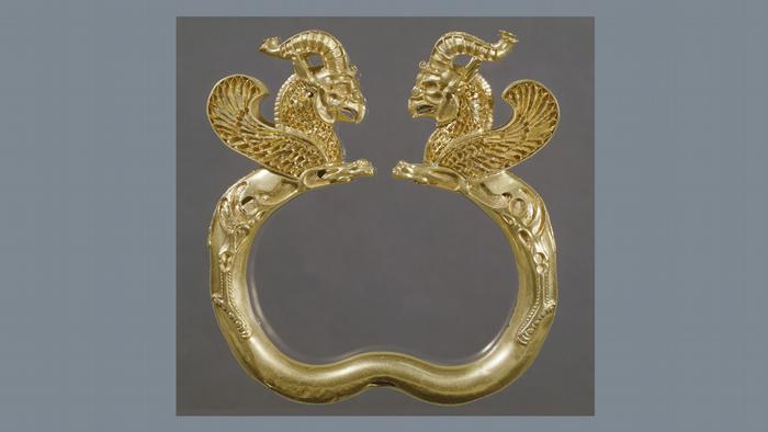 Ein goldener Armreif, der zwei mythische Geißböcke mit Flügeln darstellt.