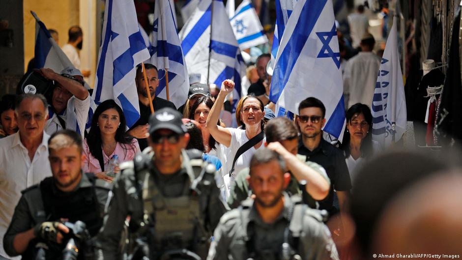 Members of Israeli security accompany Israelis lifting their national flag in Jerusalem's Old City as they mark Jerusalem Day, on 29 May 2022 (photo: AFP/Getty Images)