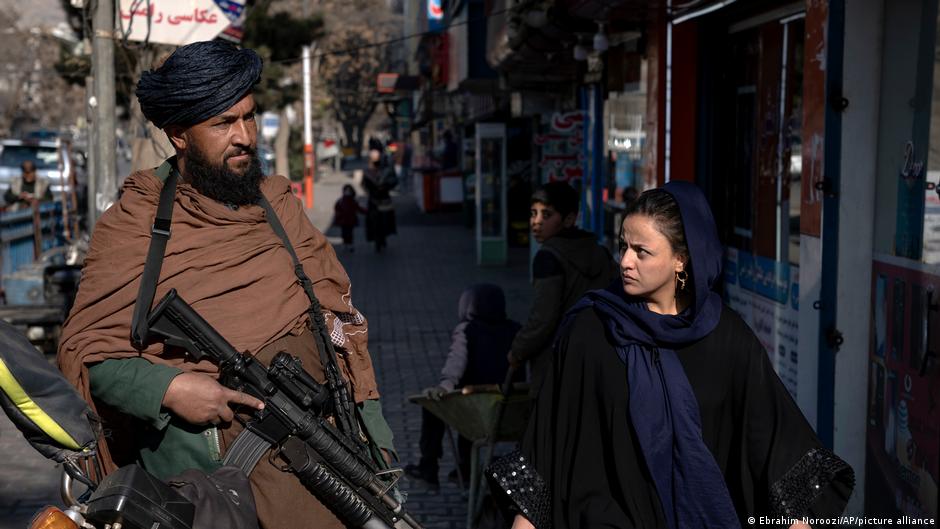 مقاتل مسلح من طالبان وامرأة أفغانية في أحد شوارع كابول. Armed Taliban fighter and Afghan woman on the street in Kabul (image: Ebrahim Noroozi/AP/picture-alliance)