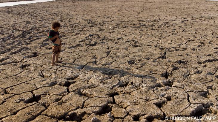 A child stands on a drought-stricken plain in southern Iraq, summer 2022 (image: Hussein Faleh/AFP)