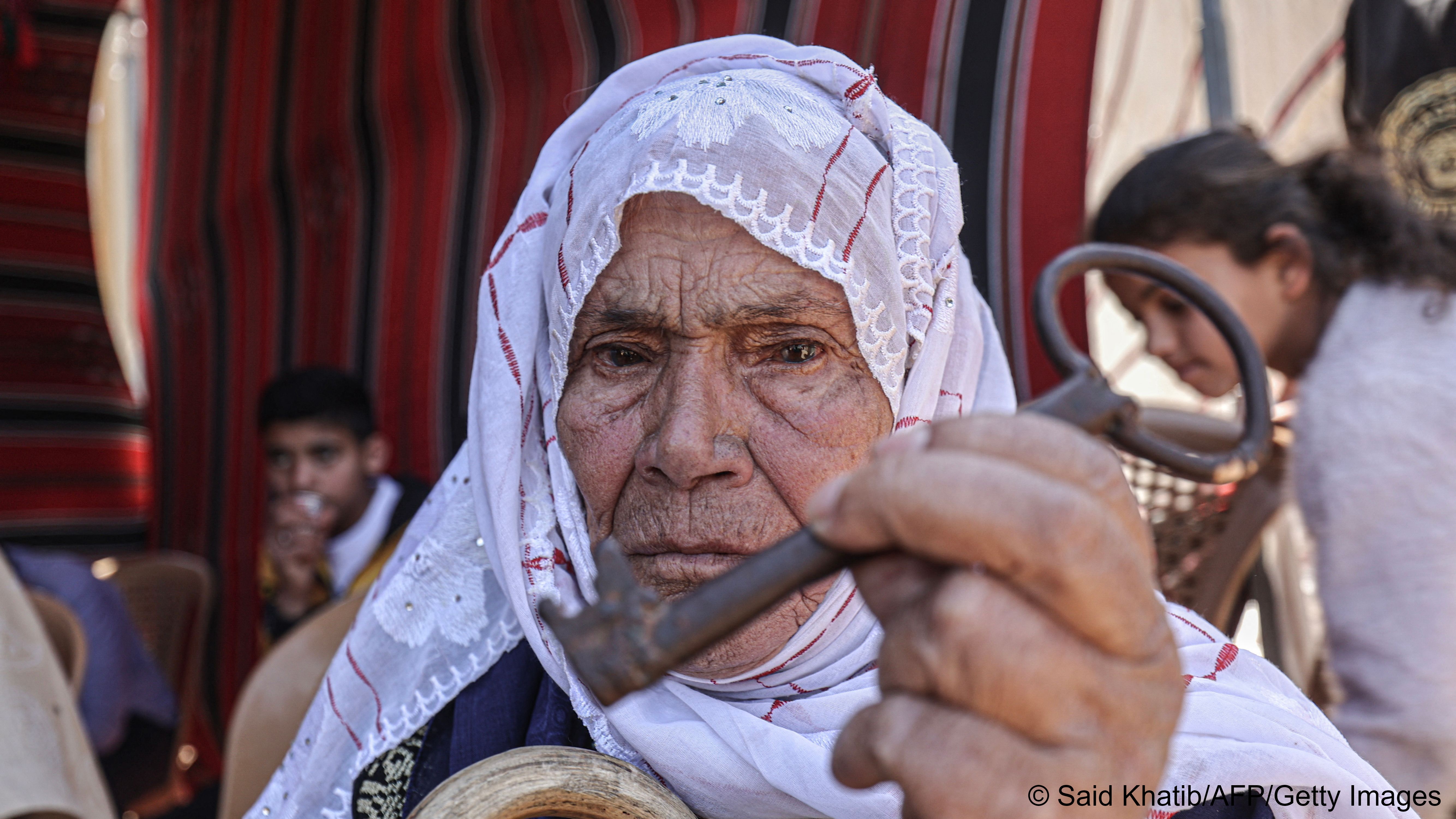 An old Palestinian woman holds up an old key (photo: SAID KHATIB/AFP)