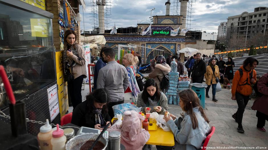 Iranian families eat fast food while shopping for Nowroz, the Persian New Year, in the shadow of a holy shrine in northern Tehran (image; Morteza Nikoubaz/Nur Photo/picture-alliance)