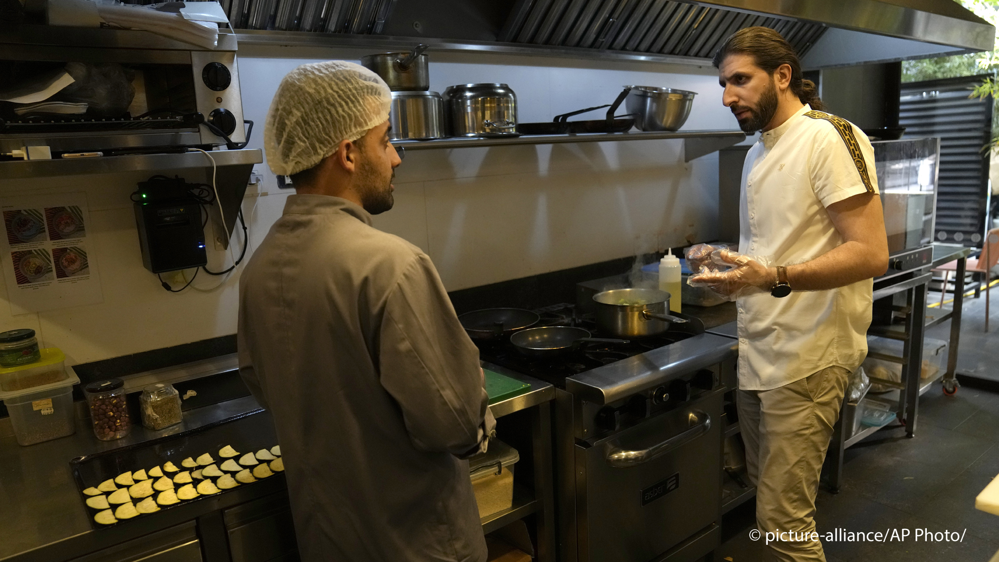 Abbas Bazzi gives directions to a chef at Le Marché Bio, the organic cafe and grocery store he co-owns, in Beirut, Lebanon, on May 30, 2023. Bazzi, who grew up in a secular family but was interested in Islam from an early age, hopes to travel to the Muslim holy city of Mecca, Saudi Arabia, for his fourth Hajj pilgrimage this month (image: AP Photo/Hussein Malla)