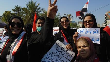 Women dressed in black carrying placards and Iraqi flags demonstrating on Tahrir Square in Baghdad, Iraq in 2019