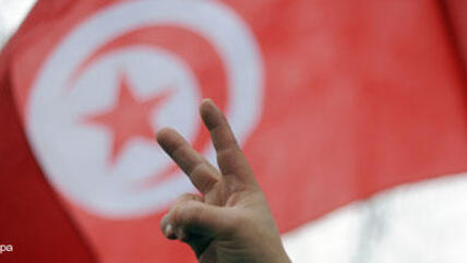 Tunisia's flag and a man showing the victory sign (photo: picture-alliance/dpa)