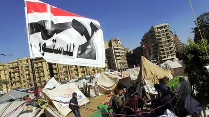 Auf dem Tahrirplatz sitzen Mursi-Gegner vor ihren Zelten, über ihnen eine Fahne mit der Aufschrift ''Nein zur Verfassung'', 10. Dezember 2012; Foto: Reuters
