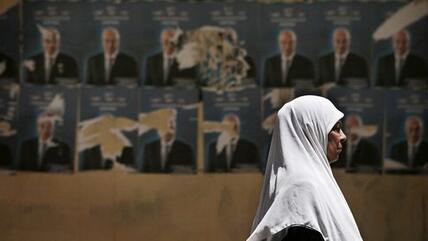 Eine Frau läuft in Kairo an Wahlplakaten für die bevorstehende Präsidentschaftswahl vorbei; Foto: AP