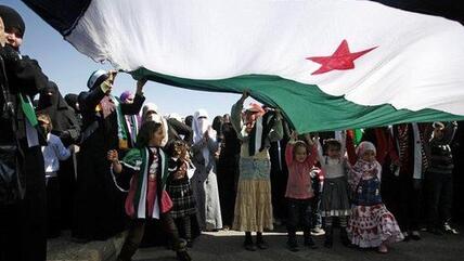 Syrische Aktivisten bei einer Anti-Assad Demonstration unter einer riesigen Flagge vor der syrischen Botschaft in Jordanien; Foto: AP/Mohammad Hannon