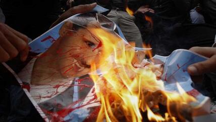 Demonstranten verbrennen ein Plakat ihres Präsidenten Baschar al-Assad vor der Syrischen Botschaft in Nicosia; dapd