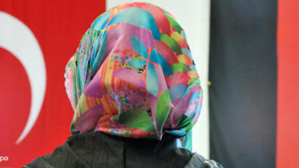 Fotomontage: Frau mit Kopftuch vor deustcher und türkischer Fahne; Foto: dpa