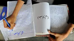 Schreibende Hand und Schreibheft in einer pakistanischen Schule 