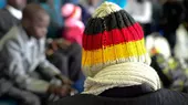 Ein Migrant mit einer Wollmütze in den deutschen Nationalfarben Rot, Gold und Schwarz