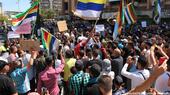 Protesters hold up placards and wave Druze flags, Sweida city, Syria, 27 August 2023