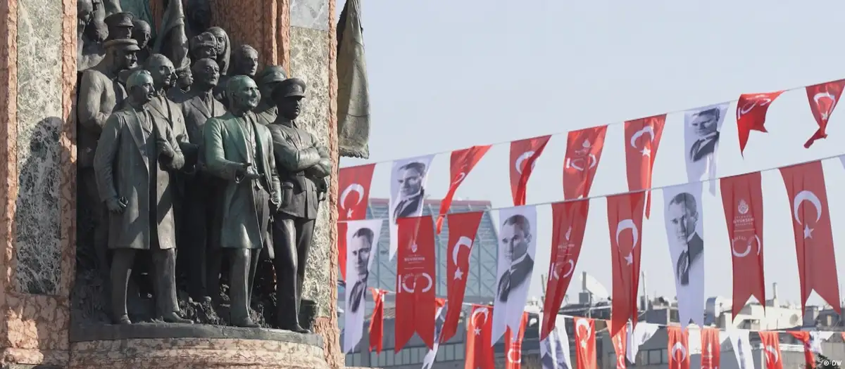 Bronze memorial dedicated to the founding of the Republic of Turkey (left) with bunting bearing Turkish national flags and images of Ataturk (right)