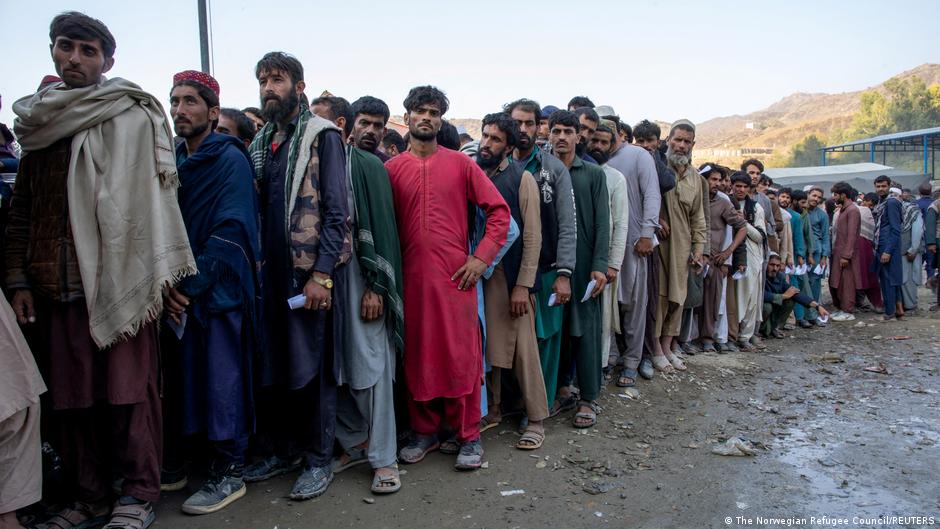 Afghan nationals stand in a queue as they wait to cross the border from Pakistan into Afghanistan
