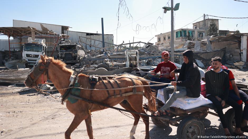 Gazan civilians travel through destroyed buildings on a horse-drawn cart in southern Gaza