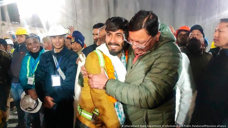 Amid a crowd of onlookers, Pushkar Singh Dhami, right, in green, Chief Minister of the state of Uttarakhand, greeting a worker, in yellow, rescued from the site of an under-construction road tunnel