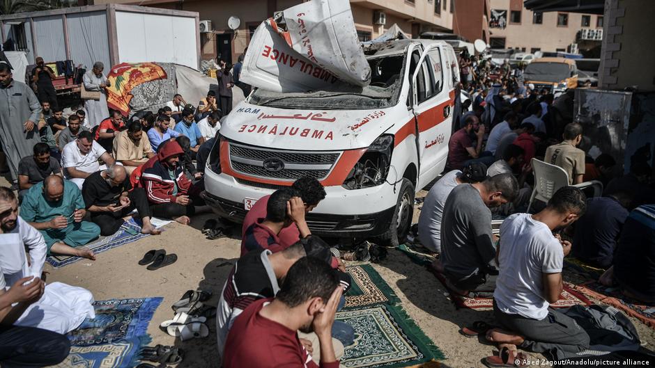 Palestinians perform Friday prayers in the courtyard of Nasser Hospital in Khan Younis, southern Gaza. An ambulance damaged in an Israeli strike is clearly visible