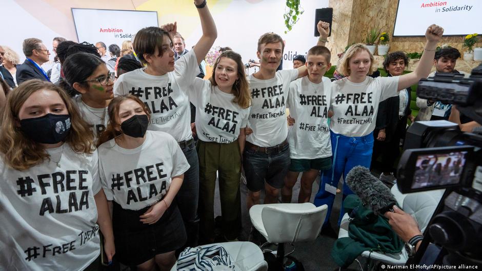 A group of young people wearing white #Free Alaa t-shirts demonstrate at COP27 in Egypt in 2022