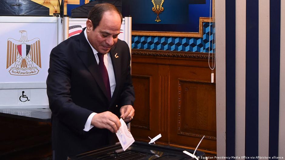 Wearing a suit, Egyptian President Abdul Fattah al-Sisi stands at a ballot box to cast his vote