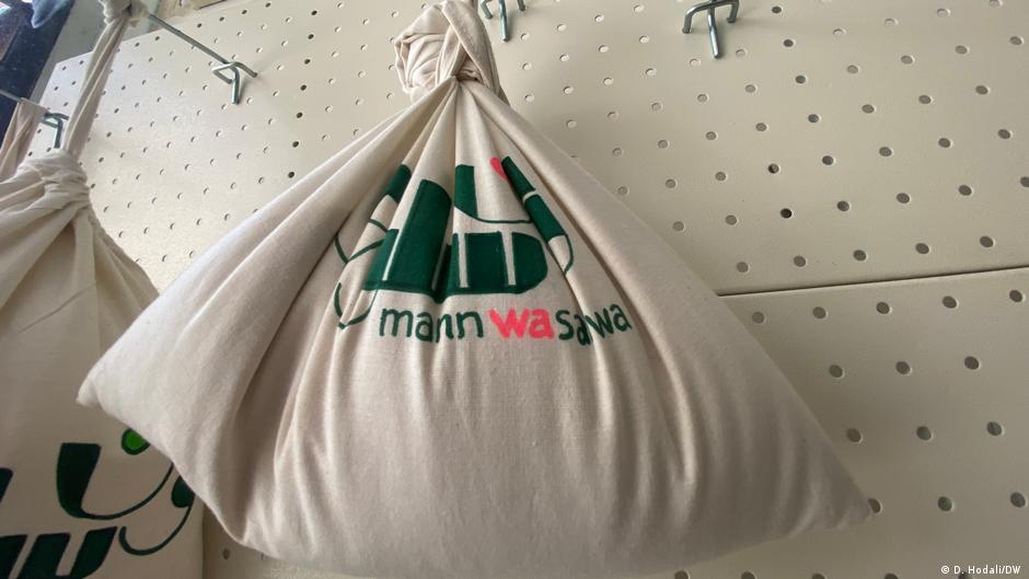 Cotton shopping bags bearing the name of the Mann wa Salwa store hang from hooks on a wall