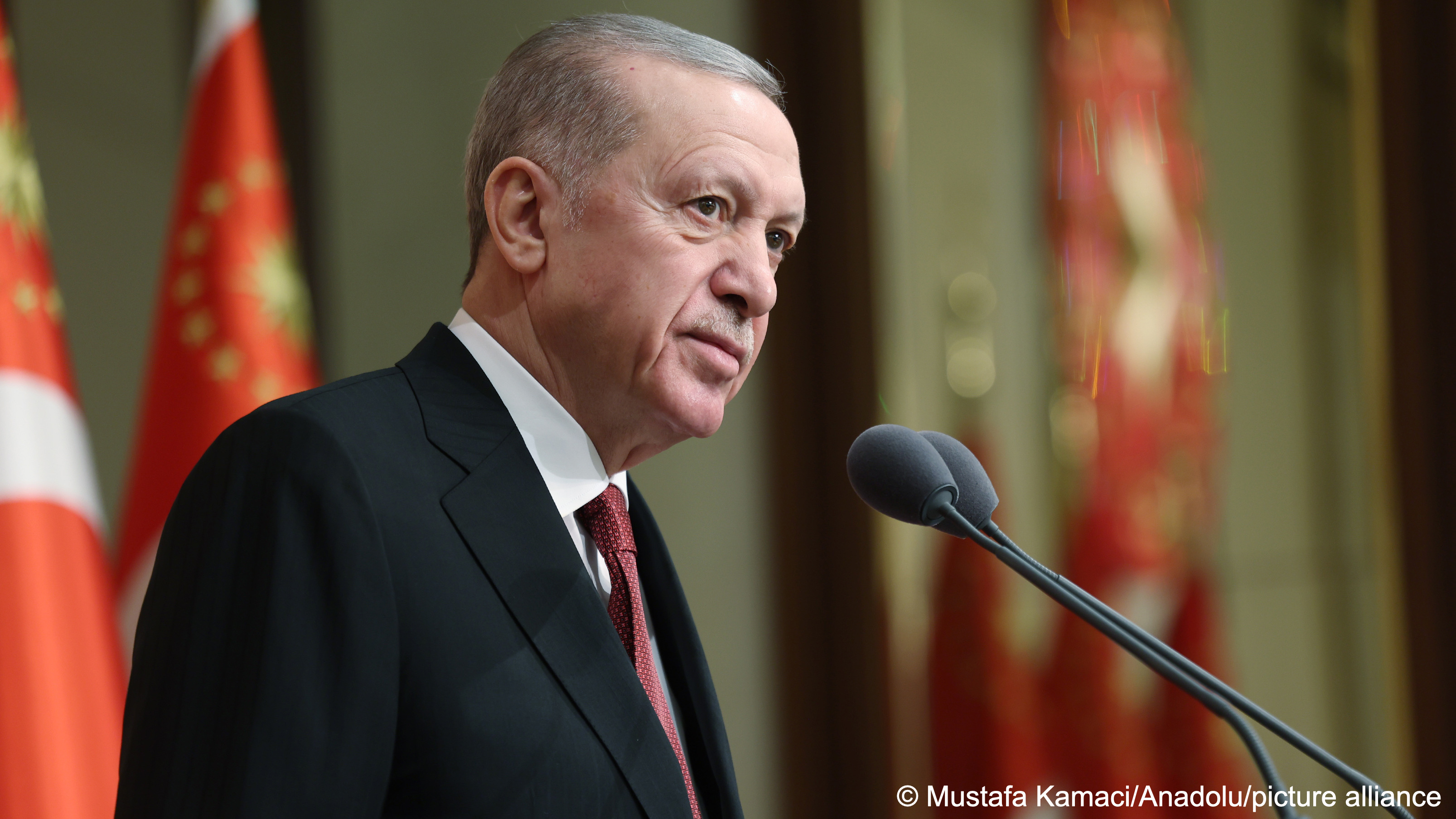 Turkish President Recep Tayyip Erdoğan stands in front of two microphones, behind him are several Turkish flags, Ankara, Turkey, 27 November 2023