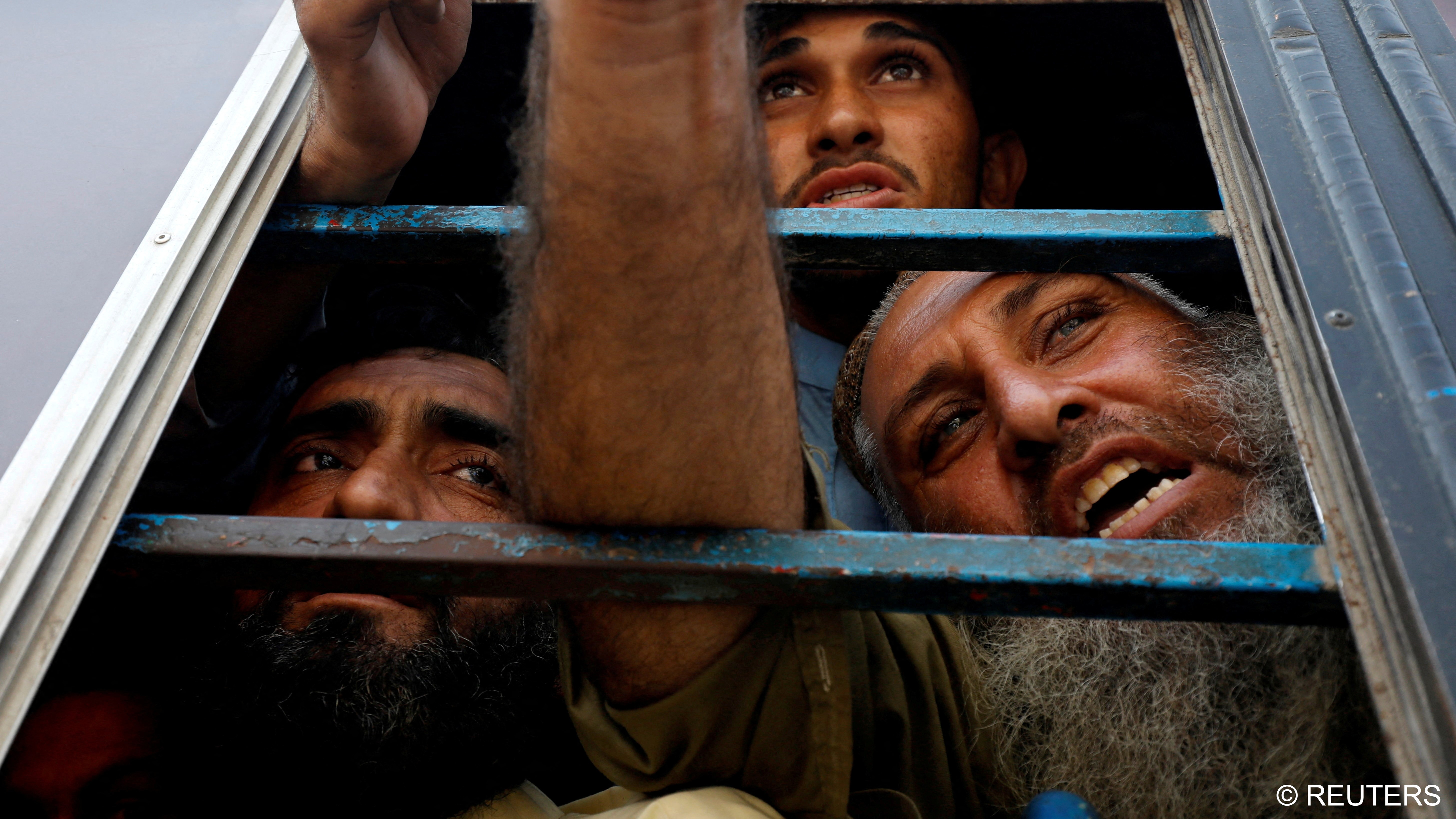 Afghan nationals, who according to police were undocumented, reach out though the window of a police bus and speak to members of the media, as they were detained and brought to a temporary holding centre, Karachi, Pakistan, 2 November 2023