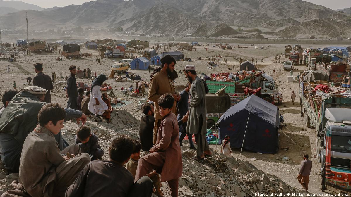 Afghan refugees gather at the border crossing in Torkham. Tents and trucks and mountains can be seen in the background 