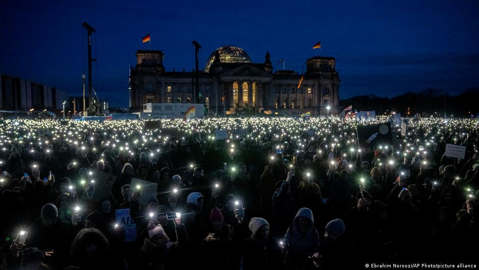 Shining their cellphone torches, people gather to protest against the AfD party and right-wing extremism in front of the Reichstag building in Berlin