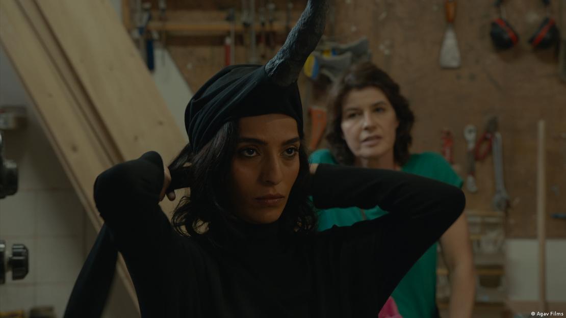 A woman in black ties up a headscarf, another woman stands behind her - film still from "Shikun" with Bahira Ablassi (front) and Irene Jacob