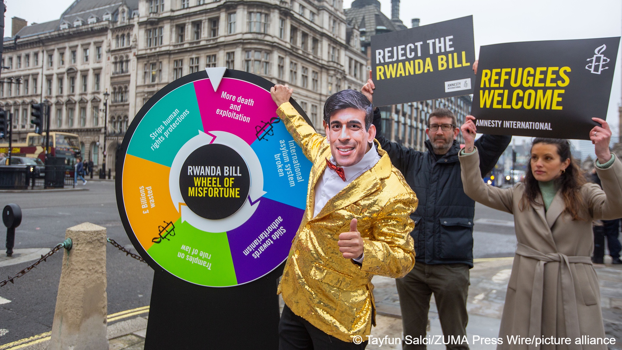 A person wearing a mask with the likeness of UK Prime Minister Rishi Sunak is seen acting as a game show host spinning a 'wheel of misfortune' to highlight the negative consequences of the government's controversial Safety of Rwanda bill in a protest stunt by Amnesty International, London, England, 11 March 2024