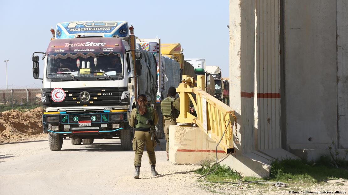 Armed Israeli soldiers watch a queue of aid trucks destined for Gaza in late 2023