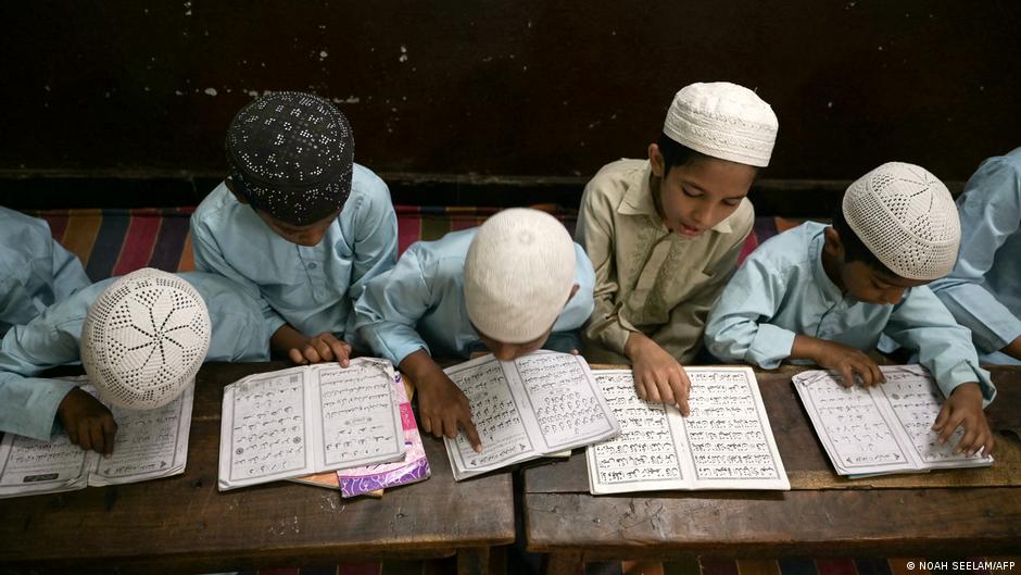 Young Koran students in Hyderabad, India, sit bent over the Koran and study