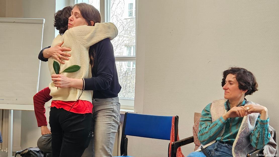 Two people hug in a room while two others look on (image: Slieman Halabi)