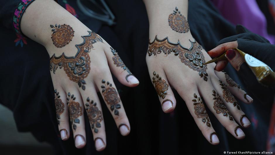 A woman shows her hands covered in henna designs