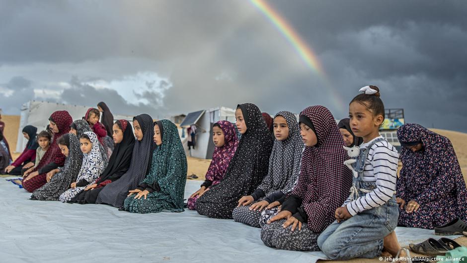 Children are seen praying outdoors
