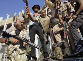 Rebel fighters gesture and shoot in the air as they celebrate overrunning Moammar Gadhafi's compound Bab al-Aziziya in Tripoli, Libya, early Wednesday, 24 August 2011 (photo: dapd)