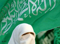 A veiled Palestinian woman stands in front of a Hamas flag as she attends a Hamas pre-election in 2006 (photo: AP)