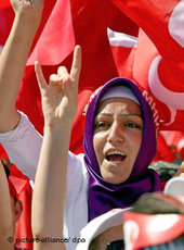 Turkish woman wearing headscarf at a protest rally; background: the Turkish natio al flag (photo: dpa)