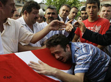 An unidentified Turkish man mourns over the flag draped coffin of an explosion victim during a funeral ceremony in Istanbul (photo: AP)