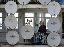 An Afghan man stands amongst several TV satellite dishes (photo: AP)