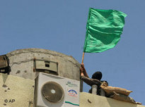 Hamas militant places a green Islamic flag on a guard tower of the Preventive Security headquarters in Gaza City (photo: AP)