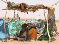 Darfur refugees, sitting under a make-shift shelter Sunday March 25, 2007, in this derelict section of Es Sallam camp say they have been waiting nine months to be relocated to decent shelters (photo: AP)